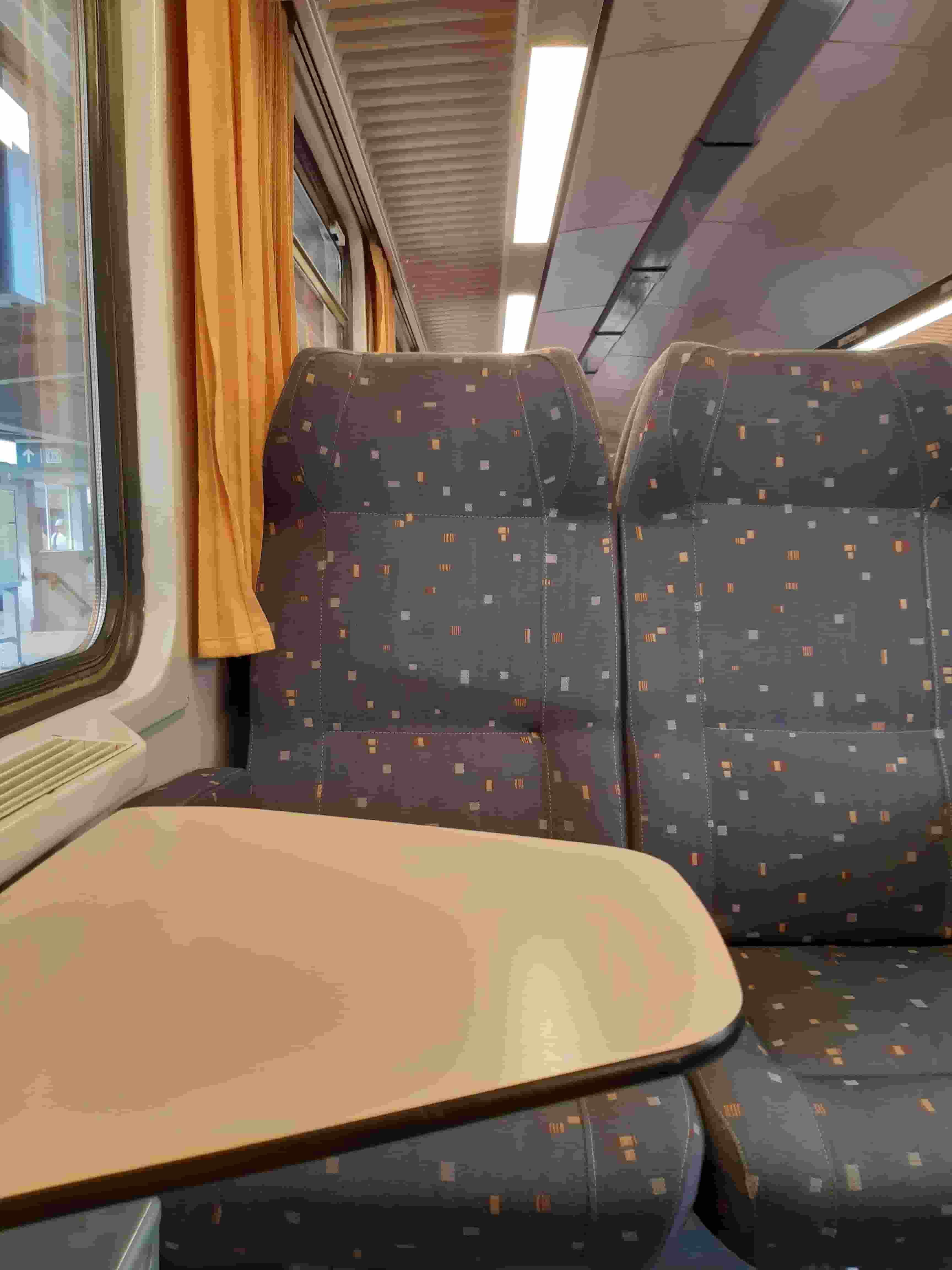 The interior of a Second Class SNCB train, showing 2 seats out of a 2+2 formation with a table in between.