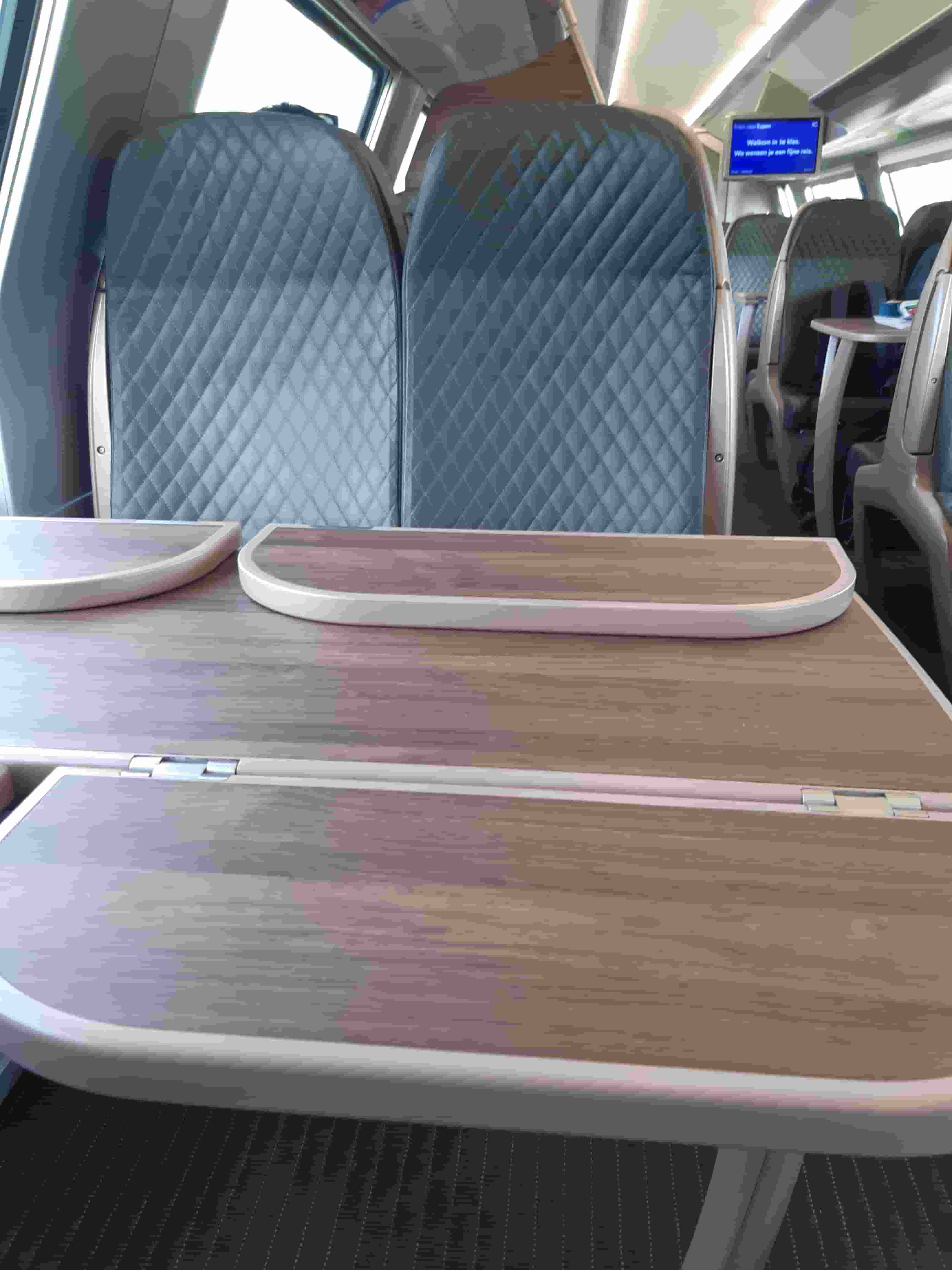 Interior of a First Class SNCB train, showing a larger table than in Second Class and comfier seats.