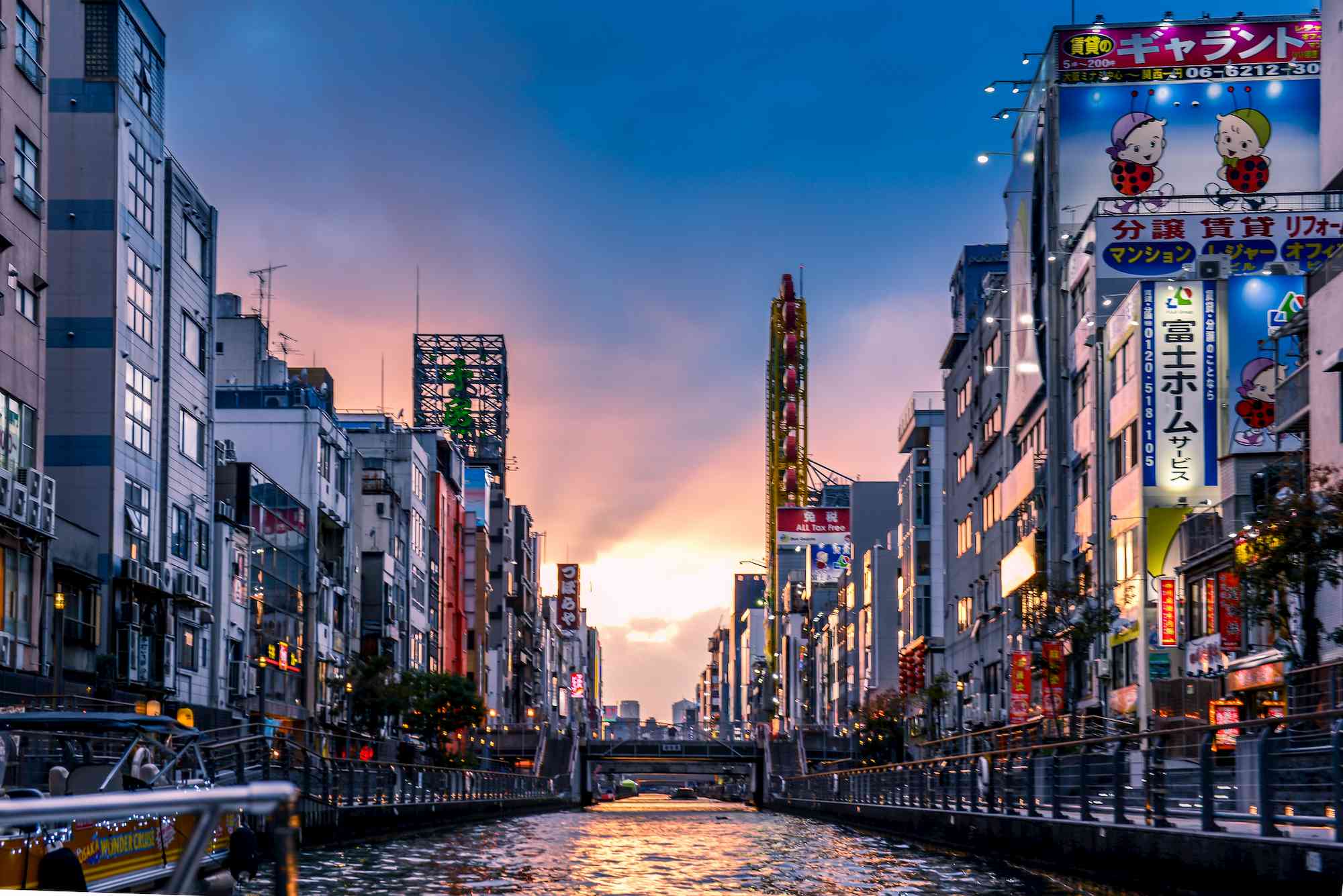 A photo of Osaka, Japan at sunset. There are tall buildings and a body of water running through the middle.