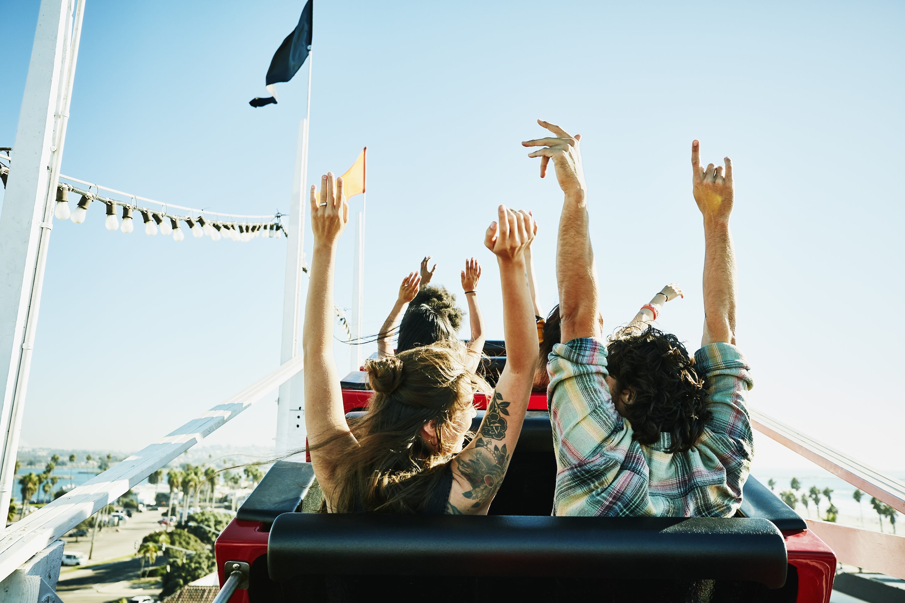 People riding rollercoaster with hands in the air before drop