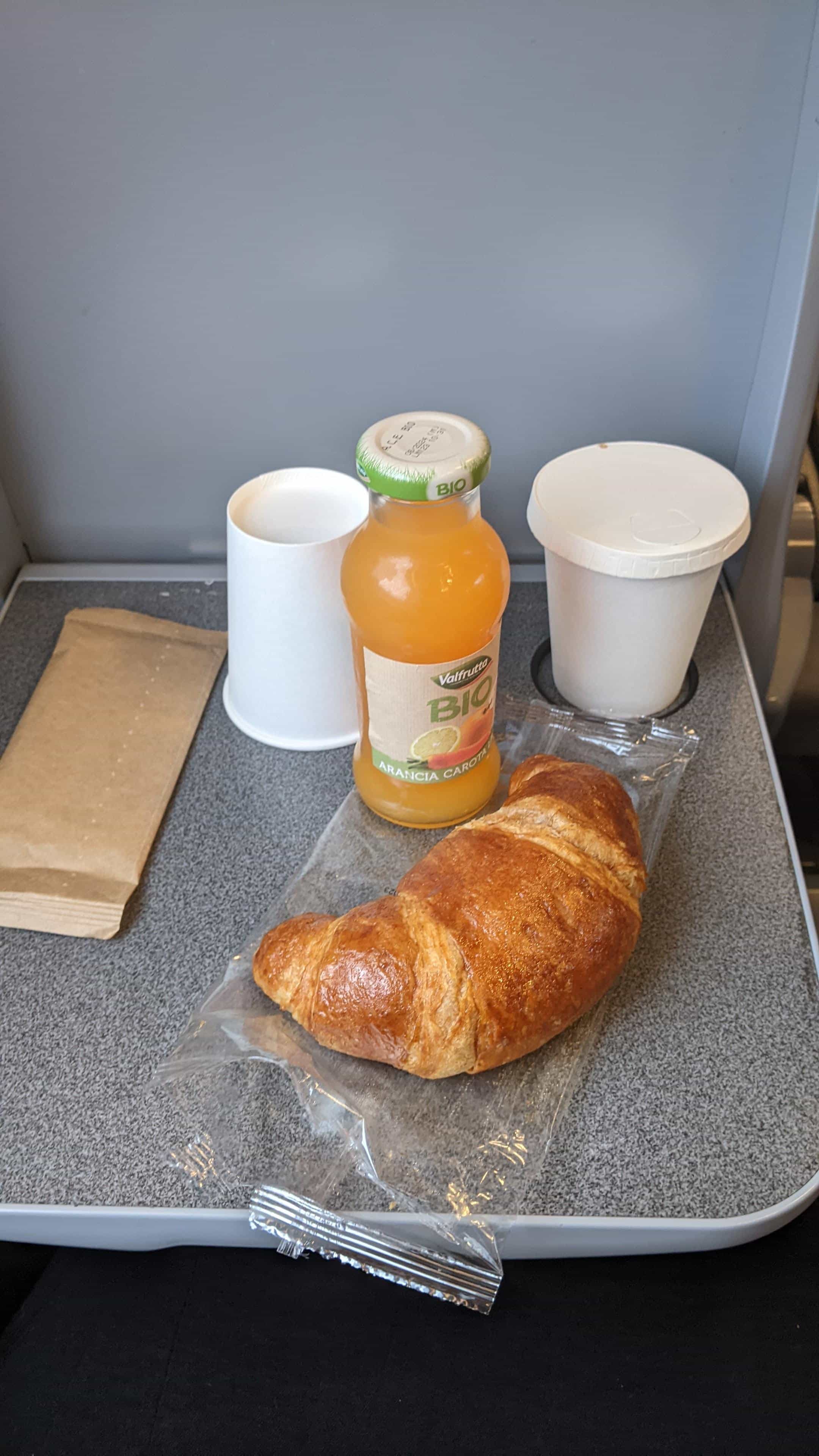 Croissant, orange juice and coffee on a fold down table on a Frecciarossa train